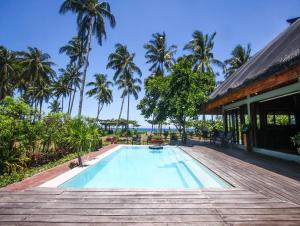 a swimming pool next to a house with palm trees at Balai sa Baibai in Mambajao