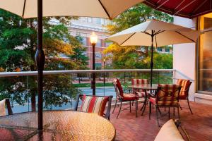 un patio con mesas, sillas y sombrillas en Residence Inn Alexandria Old Town South at Carlyle en Alexandria