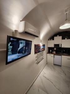 a kitchen with a flat screen tv on a wall at Suite SAN GENNARO BIS in Naples