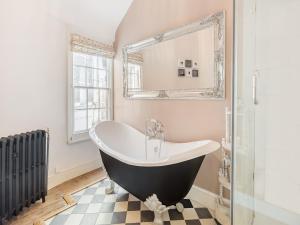 y baño con bañera, ventana y espejo. en Emilys Cottage en Broadstairs