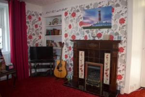 a living room with a fireplace and a guitar at Glenshee Guest House in Golspie