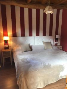 a bedroom with a large white bed with a red and white striped wall at Apartamentos Rurales CASONA DE LOLO in Caunedo