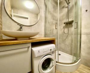a bathroom with a sink and a washing machine and a mirror at K22 Park Mokotow Aparts in Warsaw +17 photos