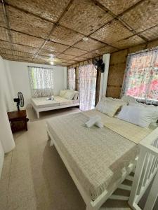 1 dormitorio con 2 camas y 2 ventanas en Lorenza 2 and 3, en Buruanga