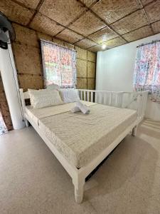 a white bed in a room with two windows at Lorenza 2 and 3 in Buruanga