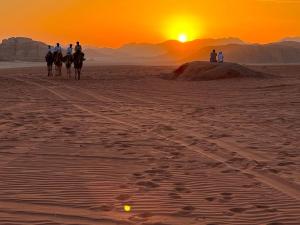 a group of people riding horses in the desert at sunset at Golden Sands Camp in Wadi Rum