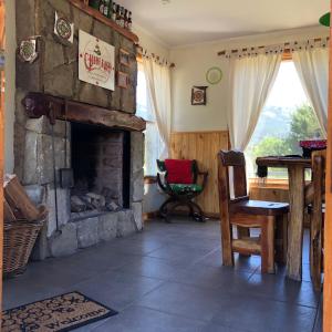 sala de estar con chimenea de piedra y mesa en Cabañas Rincón en Villa Meliquina