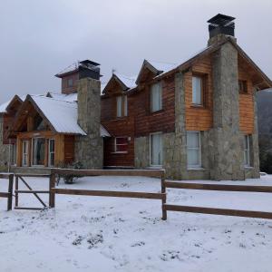 una cabaña de madera en la nieve con un banco delante en Cabañas Rincón en Villa Meliquina