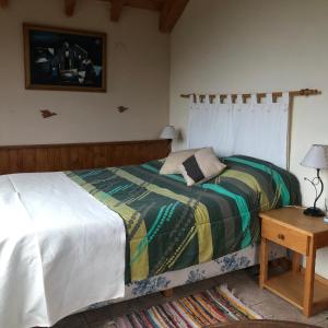 1 dormitorio con cama y mesa de madera en Cabañas Rincón en Villa Meliquina