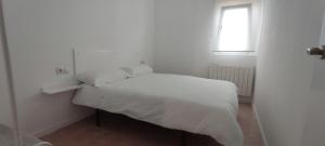 ein weißes Bett in einem weißen Schlafzimmer mit einem Fenster in der Unterkunft Estudio San Julián in Teruel