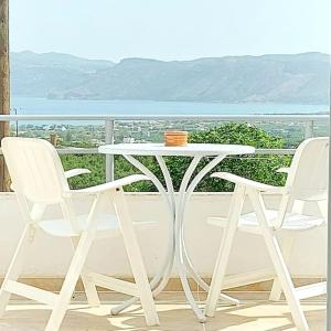 einen weißen Tisch und zwei Stühle auf dem Balkon in der Unterkunft Jacob's Sunrise cottage in Kissamos