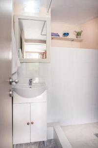 een witte badkamer met een wastafel en een spiegel bij Jacob's Sunrise cottage in Kissamos
