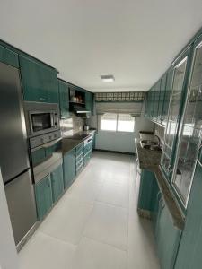 una cocina con armarios verdes y electrodomésticos de acero inoxidable en Casa Independiente Bella Vista, en Moaña