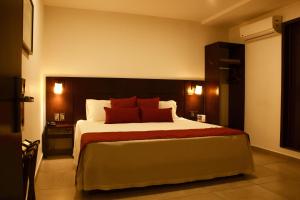 a bedroom with a large bed with red pillows at Hotel Real Alma in Oaxaca City