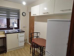 uma cozinha com armários brancos e uma mesa e cadeiras em Nice Studio Flat in Edmonton, North London em Edmonton