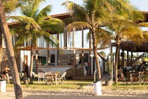 a restaurant with palm trees in front of it at Casa de Lala Beach House in São Miguel do Gostoso