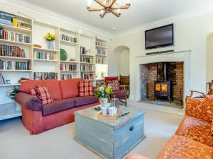 a living room with a red couch and a fireplace at Islington Hall in Tilney All Saints