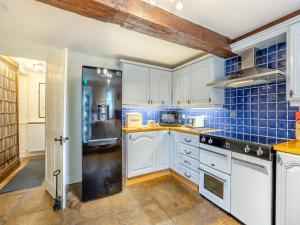 a kitchen with white cabinets and blue tiles at Islington Hall in Tilney All Saints
