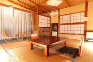 een woonkamer met een houten tafel en stoelen bij Hatsunoyu in Yamanouchi
