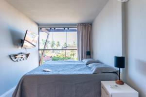 a bedroom with a large bed with a large window at Praia Central Porto de Galinhas in Porto De Galinhas