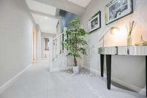 a white hallway with a potted plant and a table at Countesswells Crescent Villa ✪ Grampian Lettings Ltd in Aberdeen