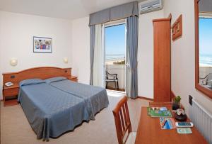 - une chambre avec un lit, une table et une fenêtre dans l'établissement Hotel Argentina, à Senigallia
