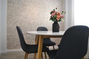 une table avec trois chaises et un vase de fleurs dans l'établissement Victoria Flat F&M Moderno, acogedor y céntrico, à Malaga