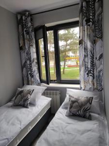 Duas camas num quarto com uma janela em Przytulne mieszkanko em Oświecim
