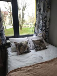 un letto con cuscini di fronte a una finestra di Przytulne mieszkanko a Oświęcim