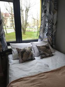 a bed with pillows in front of a window at Przytulne mieszkanko in Oświęcim