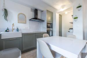 kuchnia z białym stołem i zlewem w obiekcie LB Vacation Rentals I A Quiet Place with Garden in the Heart of Cannes w Cannes
