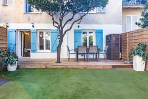 een patio met een tafel en stoelen op een houten terras bij A Quiet Place with Garden in the heart of Cannes in Cannes