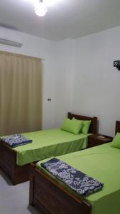 two beds in a room with green sheets at El captain Resort in Hurghada