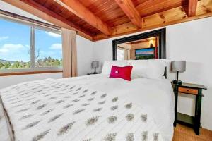 1 dormitorio con cama blanca grande y almohada roja en Cozy Moon Cabin en Big Bear Lake