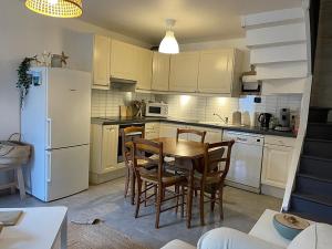 kuchnia ze stołem i krzesłami oraz białą lodówką w obiekcie Les Galets, maison avec terrasse w Étretat +8 zdjęć