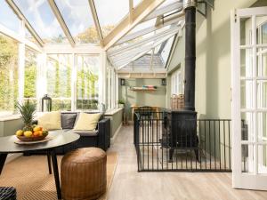 a conservatory with a living room with a wood stove at Danehurst Cottage in Sway