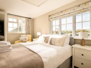 a bedroom with a large bed and two windows at Danehurst Cottage in Sway