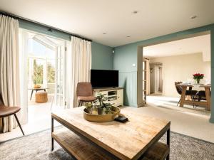 a living room with a table and a tv at Danehurst Cottage in Sway