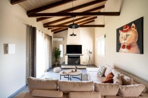 a living room with a couch and a cat painting on the wall at Meltemi Beach House - a seaside Luxury maisonnette in Dhiyeliótika