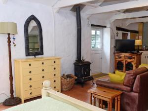a living room with a couch and a wood stove at Cowshed Cottage - Uk42668 in Ruan Major