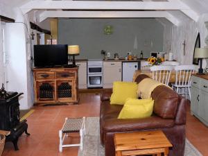 a living room with a brown leather couch and a kitchen at Cowshed Cottage - Uk42668 in Ruan Major
