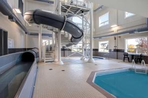 a indoor swimming pool with a slide in a building at Days Inn & Suites by Wyndham Warman Legends Centre in Warman