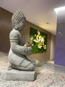 a statue of a buddha holding a glass at Doanesia Premium Hotel & Spa in Tirana