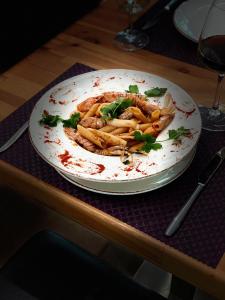 a plate of pasta on a table with wine glasses at Doanesia Premium Hotel & Spa in Tirana