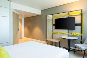 a bedroom with a bed and a flat screen tv at Courtyard by Marriott Paris Creteil in Créteil
