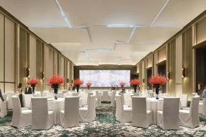 um grande salão de banquetes com mesas e cadeiras brancas em Courtyard by Marriott Luoyang em Luoyang