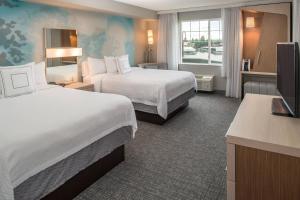a hotel room with two beds and a flat screen tv at Courtyard by Marriott Portland North in Portland