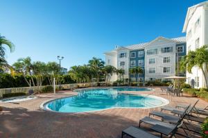 uma piscina com cadeiras e palmeiras em frente a um edifício em Residence Inn by Marriott Cape Canaveral Cocoa Beach em Cape Canaveral