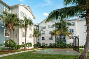 ein Apartmentgebäude mit einem Basketballplatz und Palmen in der Unterkunft Residence Inn by Marriott Cape Canaveral Cocoa Beach in Cape Canaveral