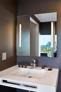 La salle de bains est pourvue d'un lavabo blanc et d'un miroir. dans l'établissement AC Hotel by Marriott Miami Beach, à Miami Beach